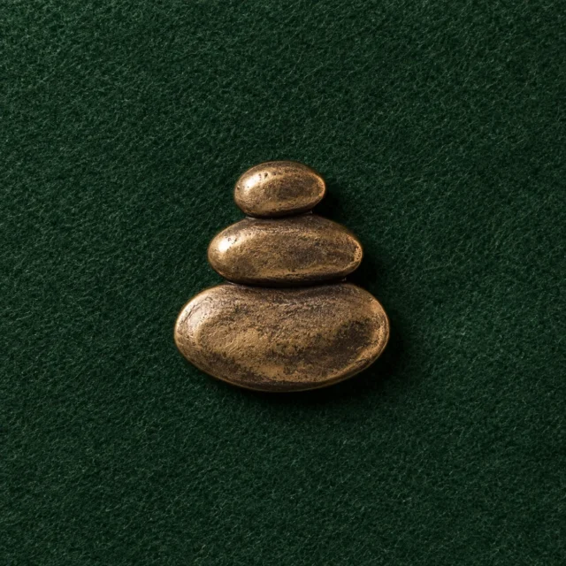 Pebble Cairn Lapel Pin, front view on green felt