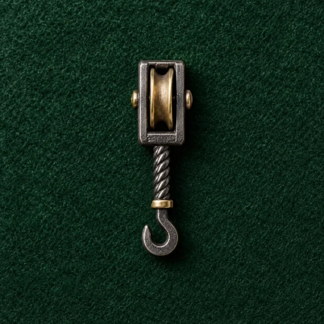 Pulley Block Lapel Pin, front view on green felt